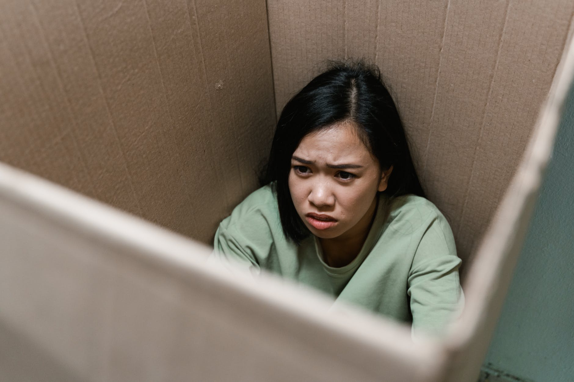 a fearful woman having claustrophobia in a cardboard box