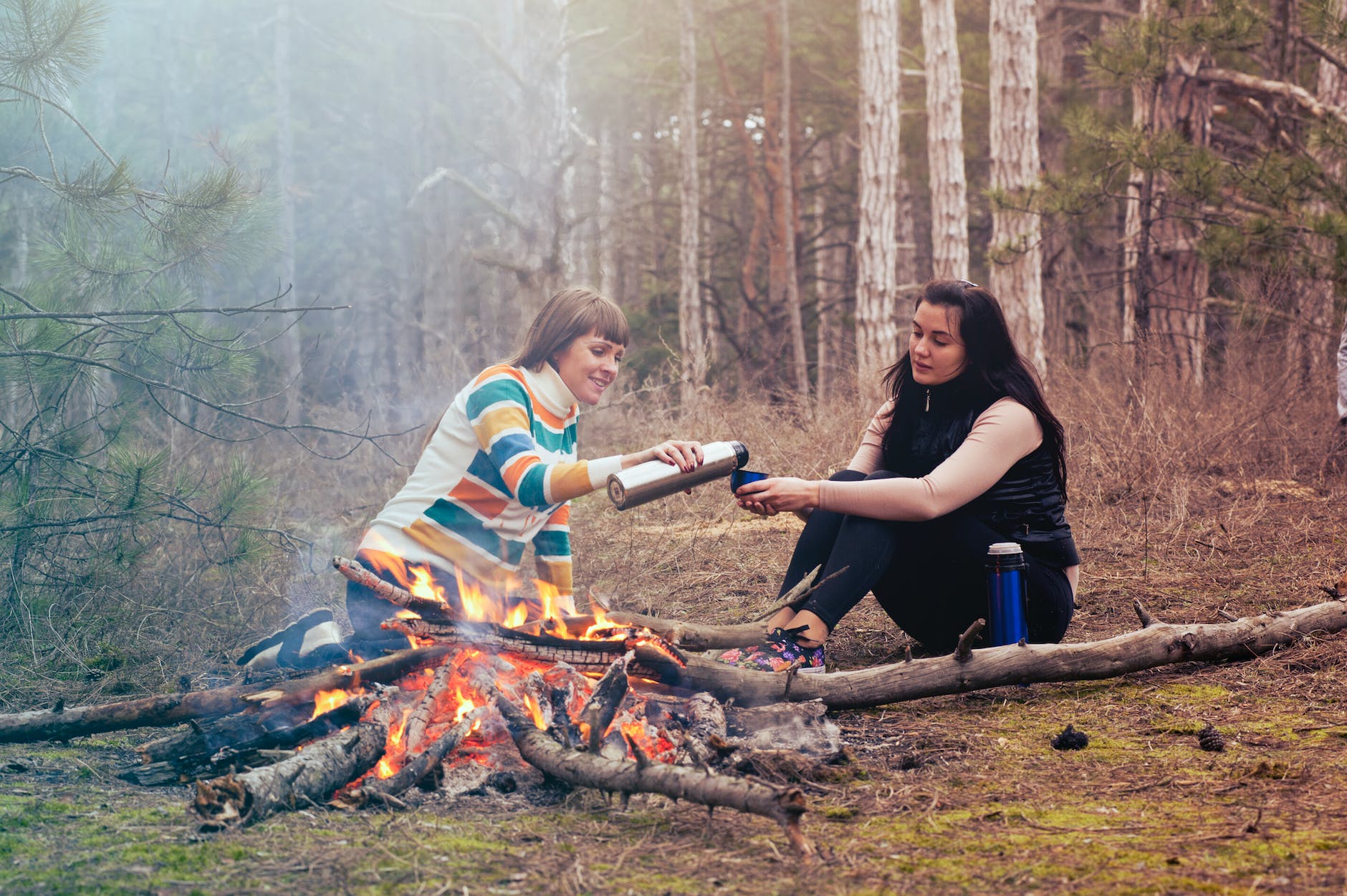 two women sitting in front of burning firewood