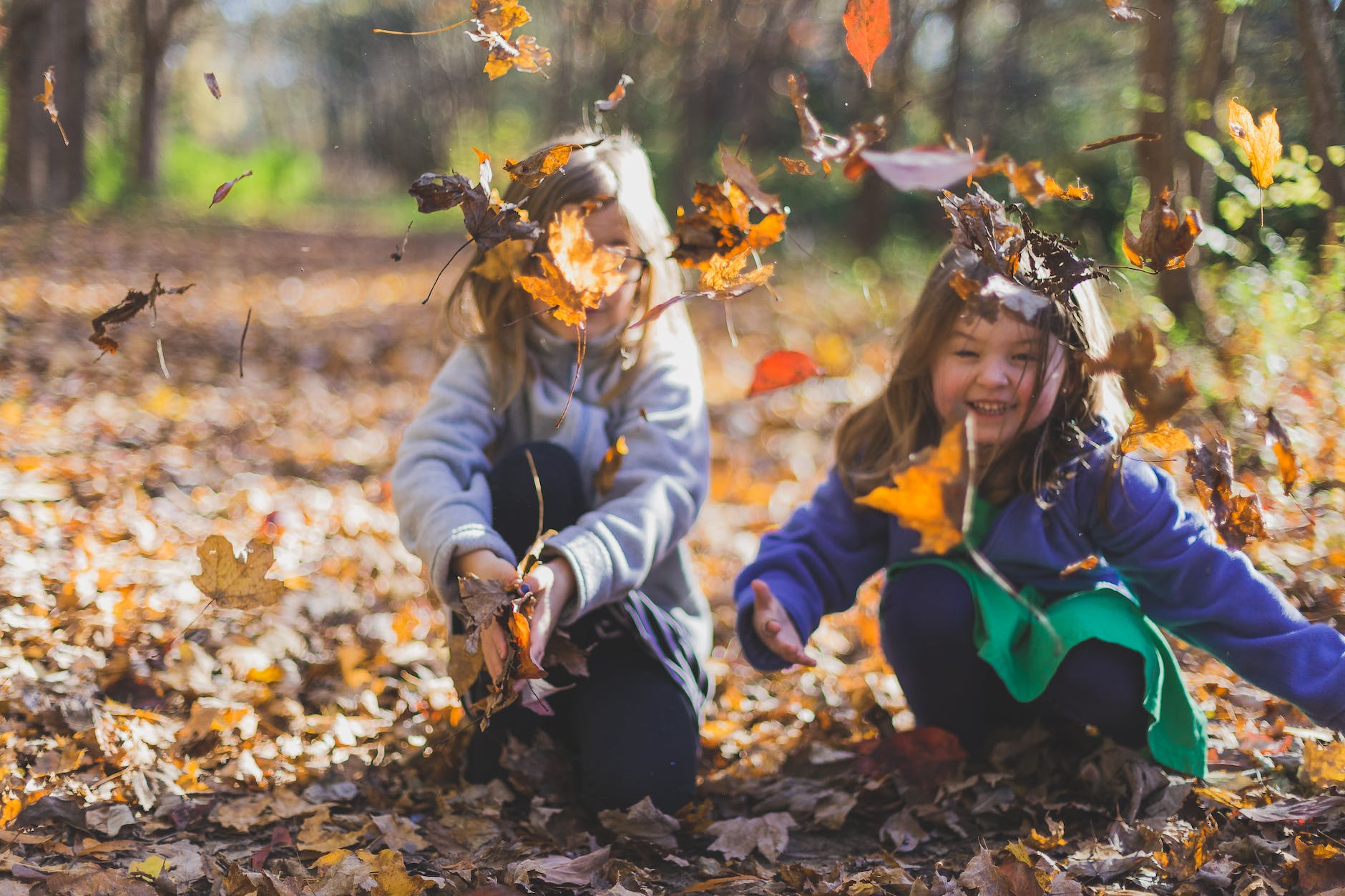 photo of children playing with dry leaves
